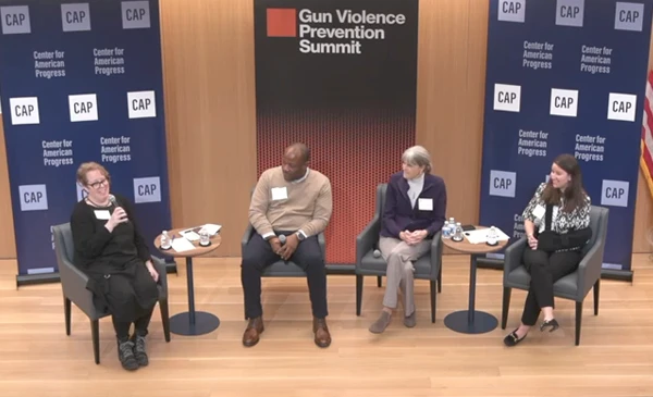Four people sitting on a stage with Gun Violence Prevention Summit banners behind them