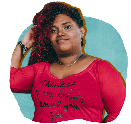 Afro-latina woman with long curly red-tinged hair wearing a red shirt that says "Think of all the beauty around you."