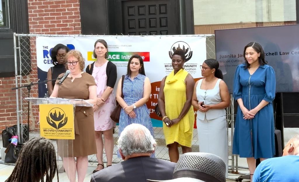 ROAR staff members standing behind podium in front of building